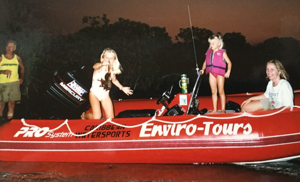 A vintage photo of an original red Caribbean Watersports Enviro-Tours boat on Florida Bay at dusk, with two children aboard