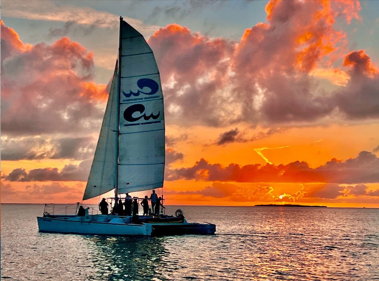 The Carolina Moon catamaran with its Caribbean Watersports sail against a fiery Key Largo sunset