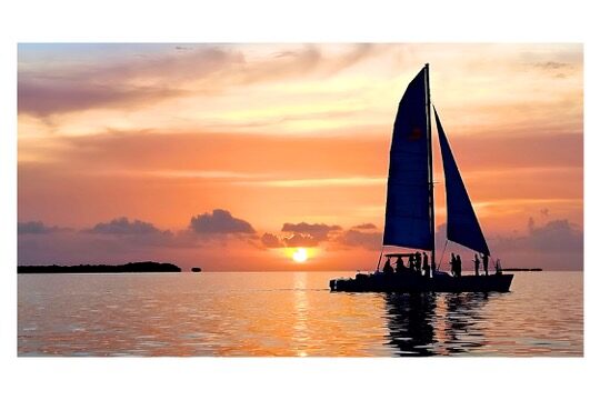 A sailing catamaran silhouetted against a soft Key Largo sunset on calm Florida Bay water