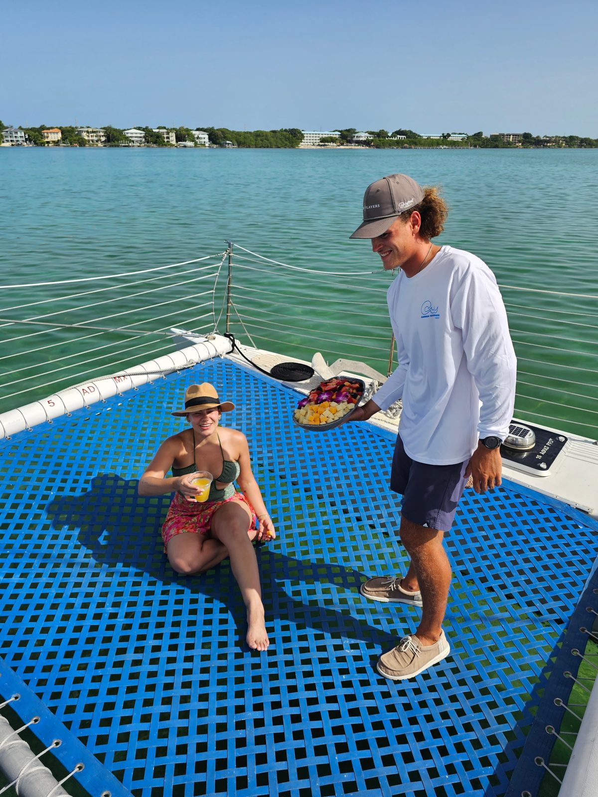 Guests standing together on the bow netting of the Carolina Moon in warm golden-hour light on Florida Bay