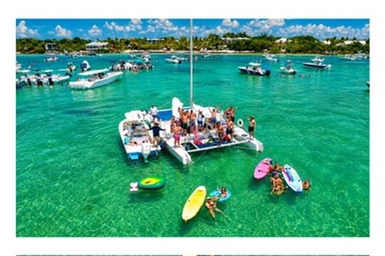 Aerial view of a Caribbean Watersports catamaran anchored at a Florida Keys sandbar with guests floating in the clear turquoise shallows
