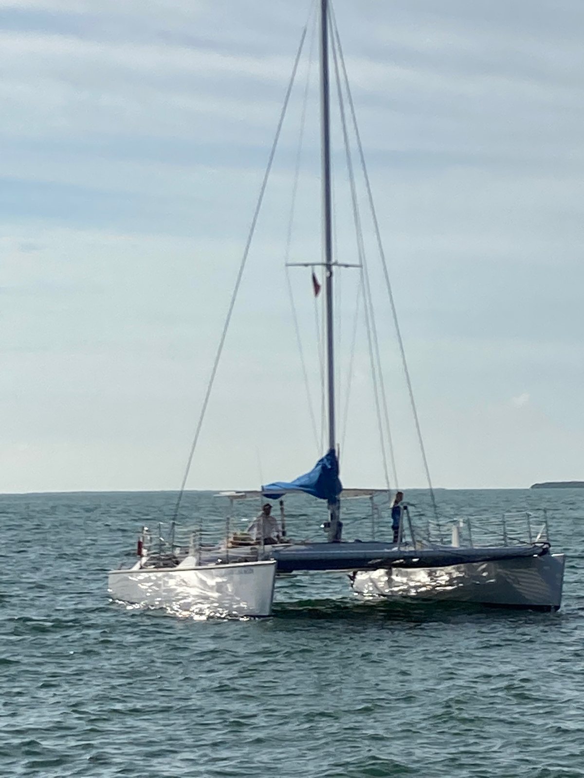 A white sailing catamaran resting on her mooring under a blue sky
