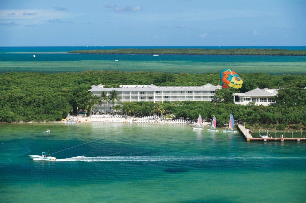 Aerial photo of the resort watersports beach with a parasail boat, sailboats and swimmers